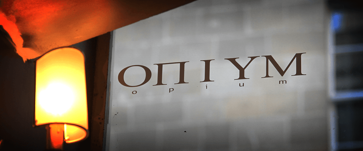 The OPIUM wall sign lit by a single warm sconce at the entrance.
