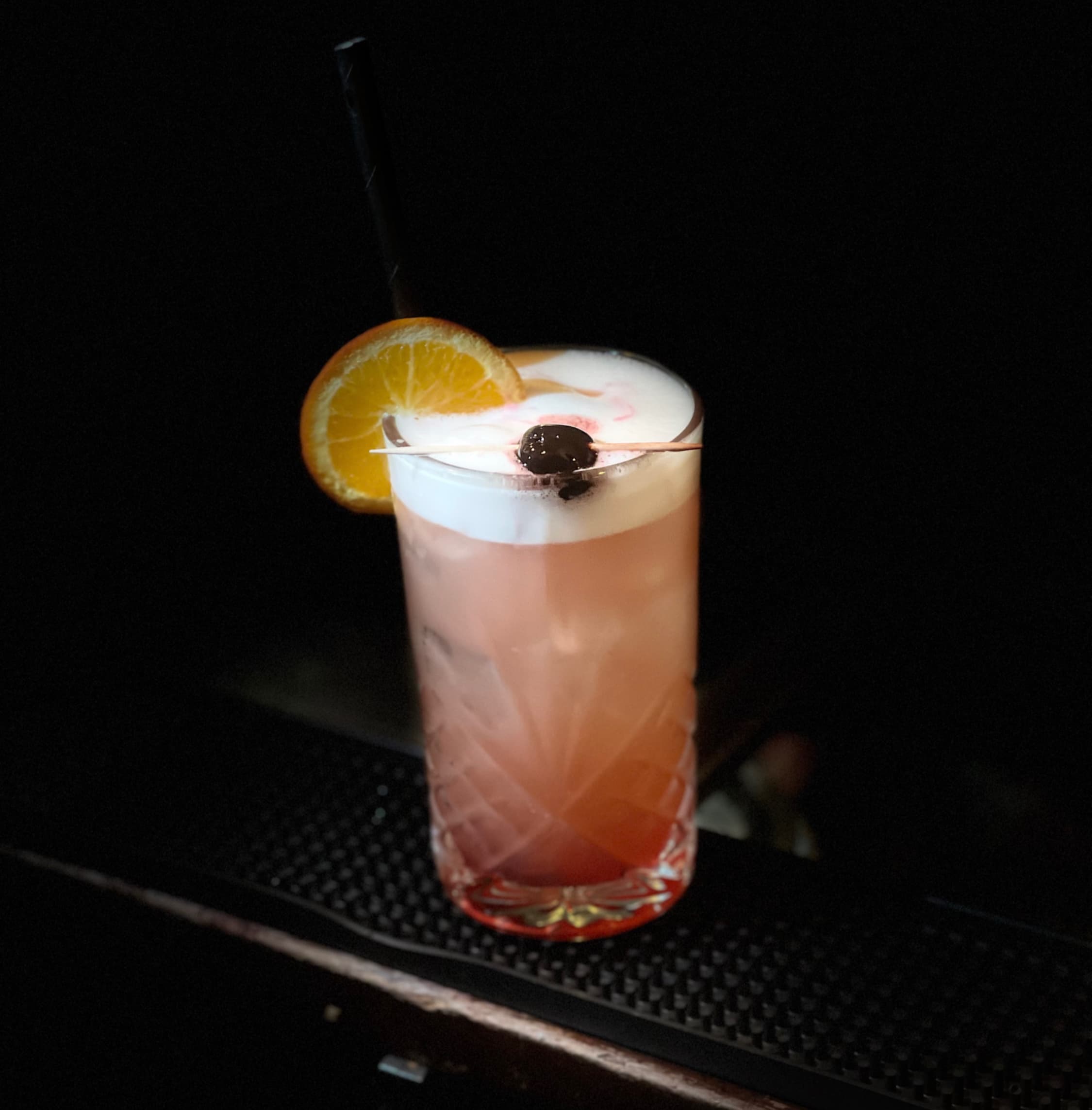 A signature Opium cocktail glowing amber in low candlelight.